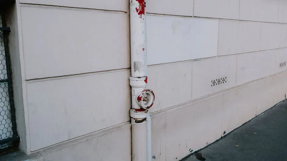 Close-up of a weathered drainpipe on an urban wall, showing signs of wear.